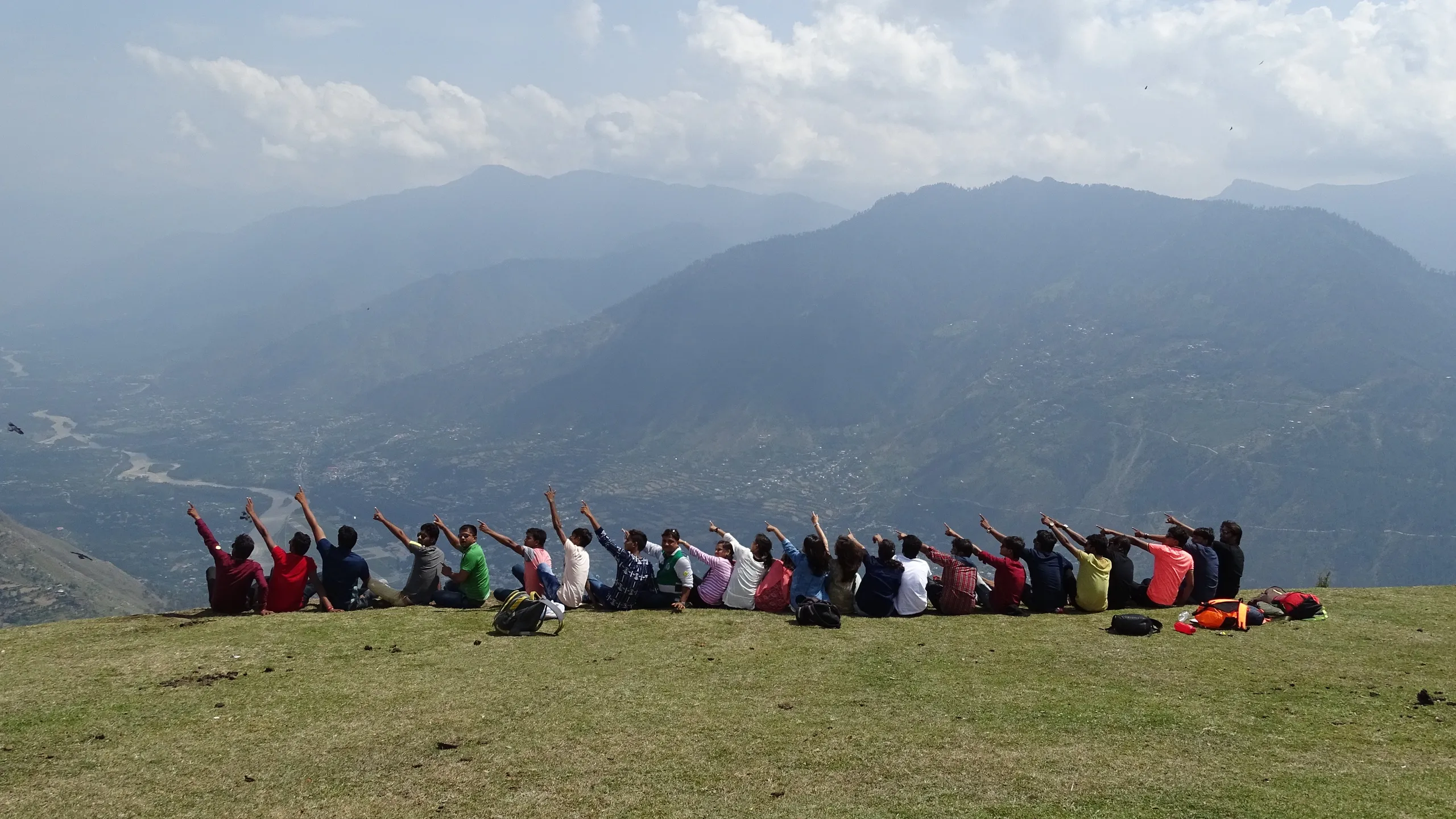 A student travel group pointing across a Himalayan valley