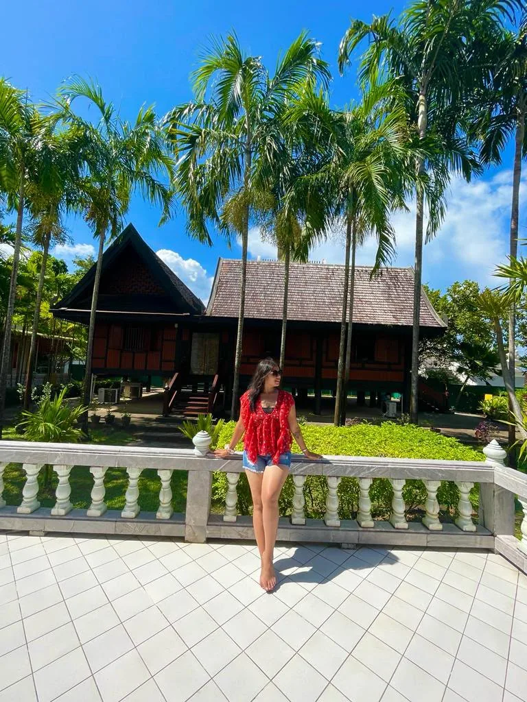 Two travellers beside a timber lodge in a tropical landscape