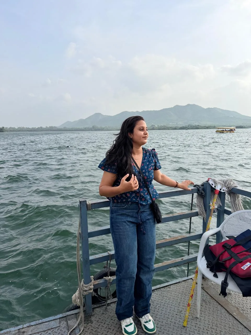 A traveller on a boat with hills beyond the water