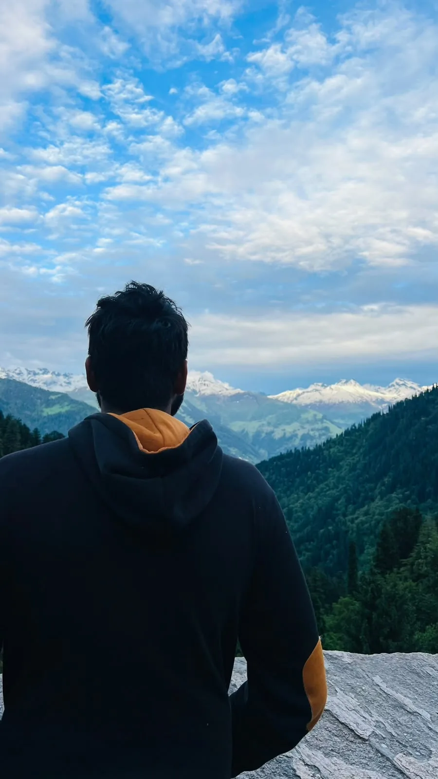 A traveller looking across a green Himalayan valley